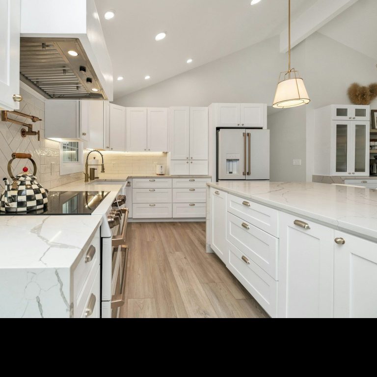 Cocina moderna con muebles blancos, encimeras de mármol y una estufa negra.
