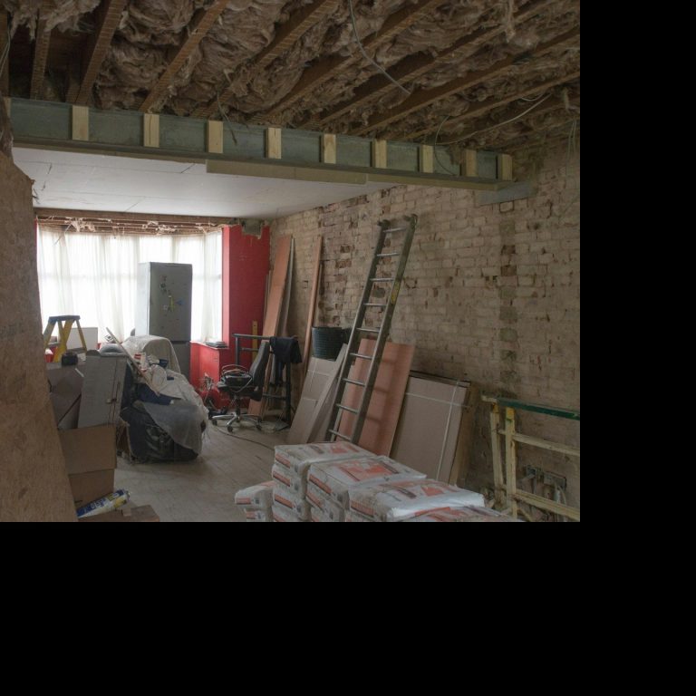 Espacio en construcción con materiales apilados y una estructura de viga visible.