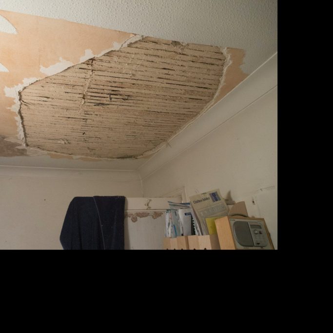 Techo desprendido con manchas y superficies desnudas en una habitación.