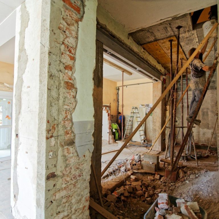 Obra en construcción con paredes de ladrillo expuestas y estructuras de soporte visibles.
